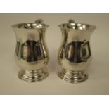 A pair of silver baluster shaped one pint mugs with hollow acanthus topped,