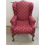 An early 20thC wingback armchair, the fabric upholstered back,