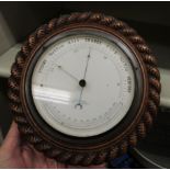 An Edwardian H Hughes of London aneroid barometer with a white enamel dial, on a rope carved,