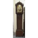 A profusely carved oak longcase clock, having a round arched hood, finials and flank pillars,