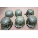 Six similar German World War II pattern military steel helmets with various insignia and some