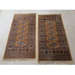 A pair of Bokhara rugs with a column of five guls on a camel coloured ground 28'' x 51'' BSR