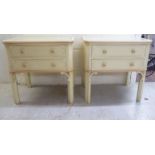 A pair of modern cream painted bedside tables, each with a glass panelled top and two drawers,