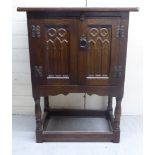 A 20thC Jacobean design oak bedside cabinet with twin Gothic inspired, carved doors,