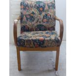 A Parker Knoll teak framed open arm chair, the floral patterned fabric covered back and seat,