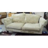 A modern two person settee with a level back and arms, upholstered in beige coloured fabric,