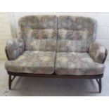 An Ercol dark stained beech and elm framed two person, open arm settee,