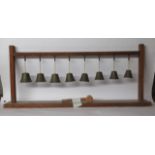 A set of eight graduated brass bells, hanging in a 1920s oak,