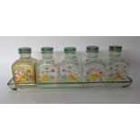 A set of five early 20thC glass dressing table jars of shouldered box design, on a tray,