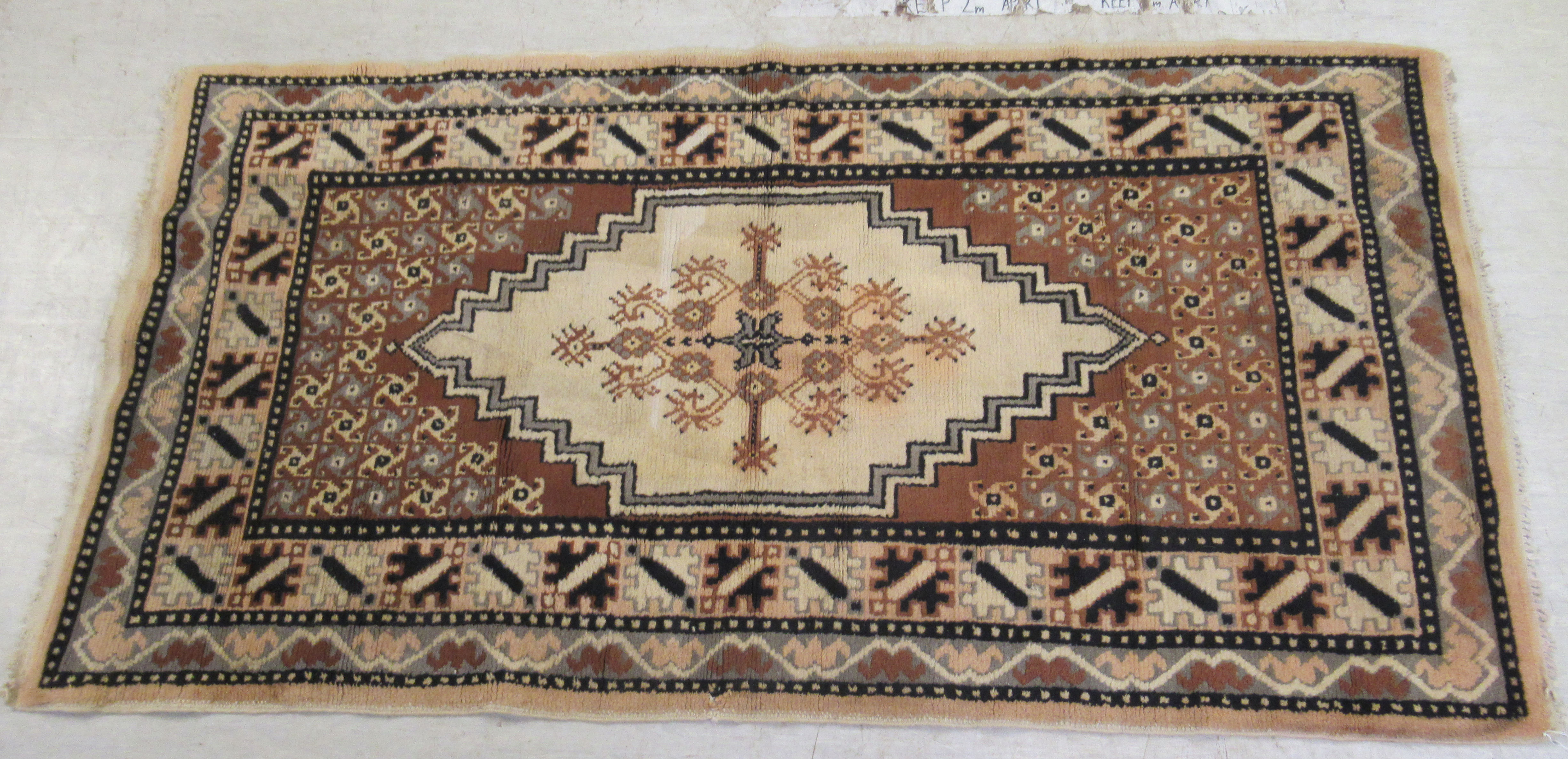 An Indian woollen rug, decorated with stylised designs,