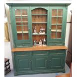 A modern farmhouse style green painted pine dresser with an arrangement of glazed cupboards and