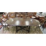 An Ercol dark stained beech and elm dining table, the oval top raised on ring turned,