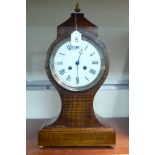 An early 20thC mahogany cased mantel clock of waisted balloon form with a four square,