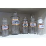 A series of five clear glass chemist's jars of cylindrical form with ground stoppers and labels 6..