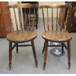 A pair of late 19th/early 20thC beech and elm framed, spindled comb back kitchen chairs, the solid,