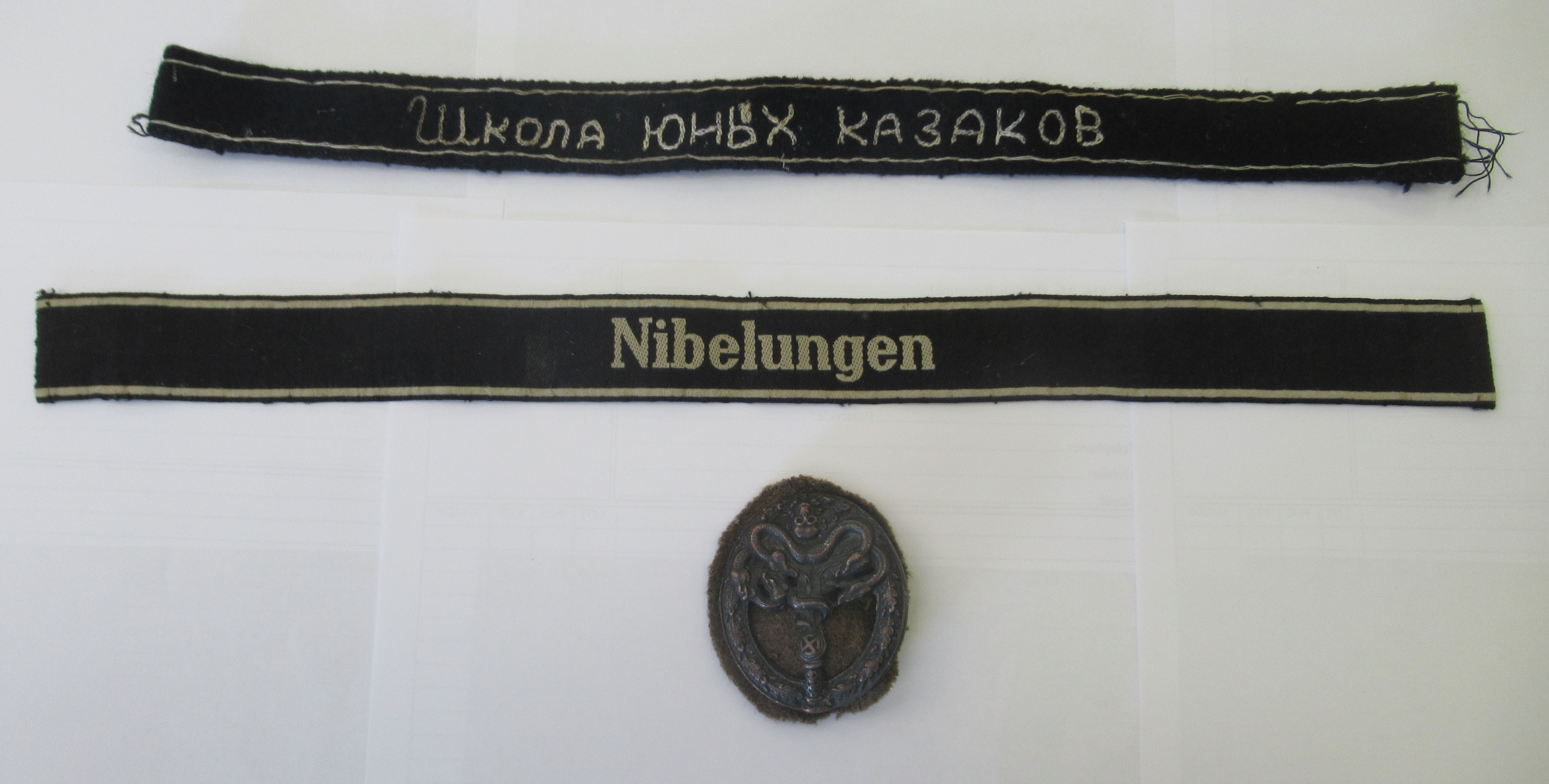 Two embroidered cuff titles (Wkona 10HBX K173 AK0B and Nibelinger); and an oval, bronzed brooch,