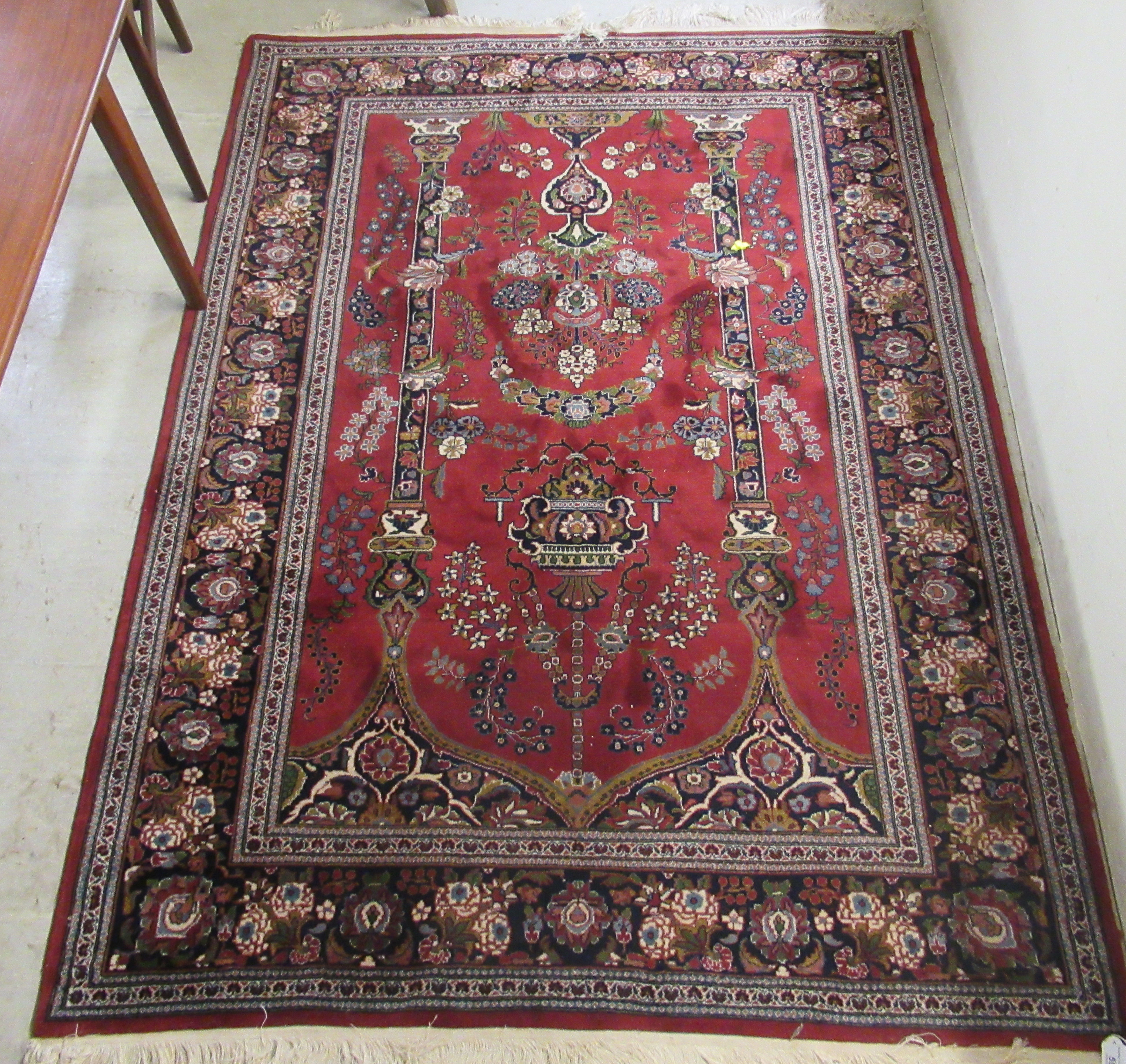 A Persian rug, decorated with pillars, a vase and flora,