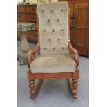 A late Victorian bleached mahogany open arm rocking chair with a high back and cushion seat,