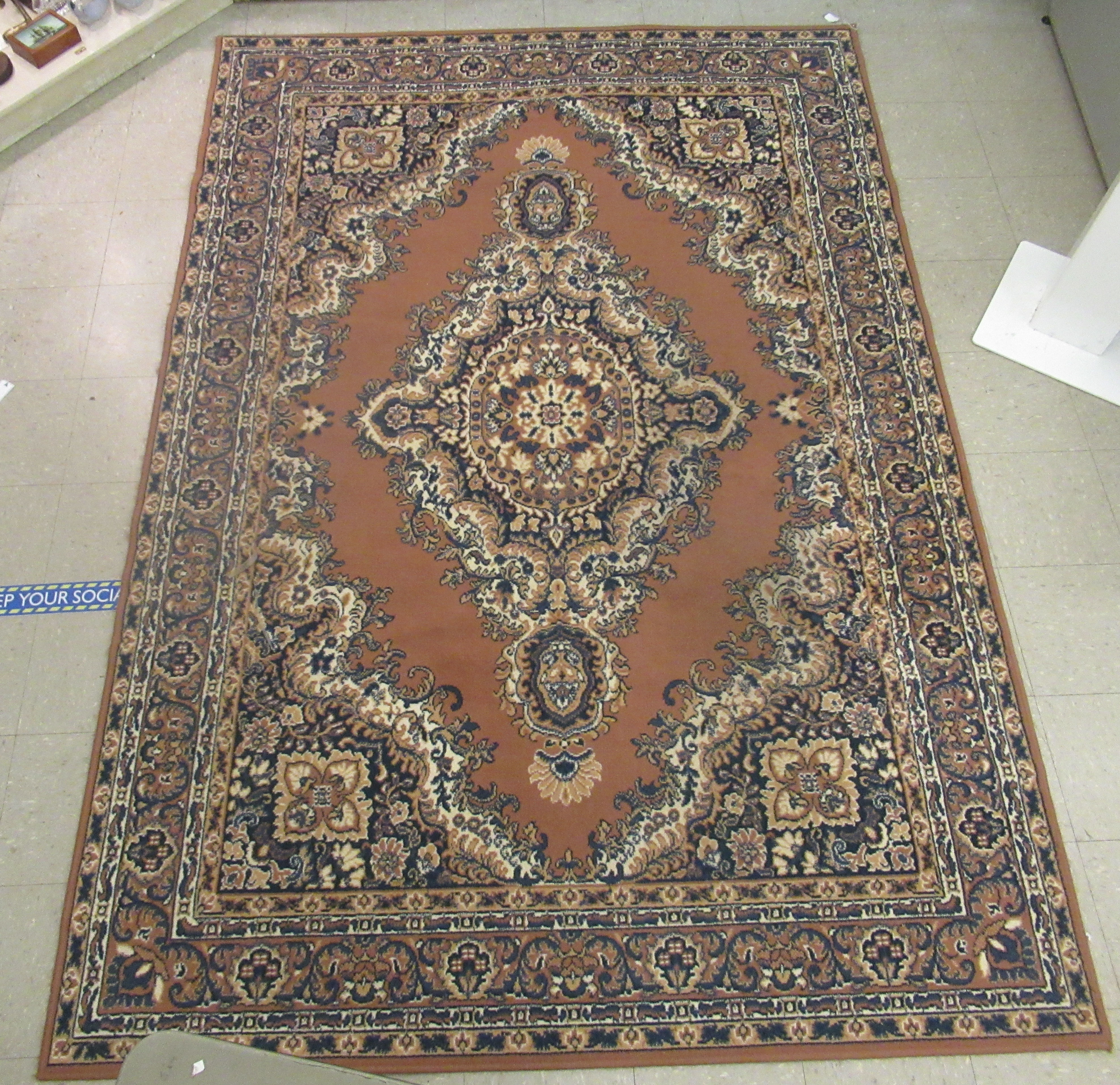 A machine made woollen rug, decorated with repeating squares of floral ornament,