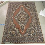 A machine made woollen rug, decorated with repeating squares of floral ornament,