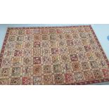 A machine made woollen rug, decorated with repeating squares of floral ornament,