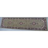 A machine made woollen runner, decorated with repeating stylised designs,