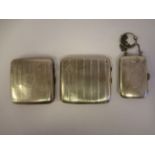 Three similar silver cushion shaped, folding cigarette cases, one with a chain handle  mixed marks