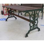 A Victorian style slatted teak terrace table with C-scrolled cast iron supports  26"h  55"w