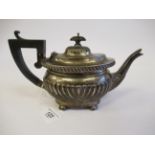 A silver teapot of oval demi-reeded design with a swept spout, hinged lid and ebonised handle, on