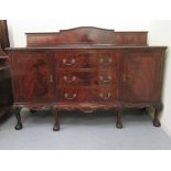 A 1920s mahogany sideboard with an arrangement of three drawers/two panelled doors, raised on