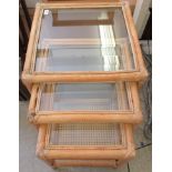 A nesting set of three bamboo framed occasional tables, each with a glazed top  largest 18"h  19"sq
