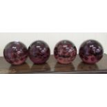 A set of four clear and purple coloured glass paperweights with interior bubble ornament  6"h
