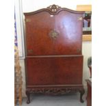 A mid 20thC Waring & Gillows walnut finished cocktail cabinet with four doors and a carved apron,