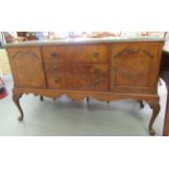A mid 20thC Waring & Gillows walnut finished sideboard with a carved edge, comprising three drawers,