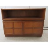 A Nathan teak low side cabinet with an open shelf, over a pair of panelled doors, on a plinth  30"h