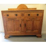 An Art Deco light oak sideboard with an arched panelled upstand, over two drawers and a pair of