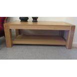 A modern light oak coffee table, raised on square legs, united by an undershelf  18"h  47"w