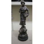 A 20thC spelter figure, a woman carrying bread in a basket, on a plinth  23"h