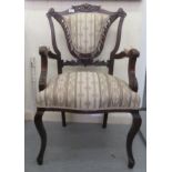 A late Victorian mahogany framed salon chair with a carved shield shaped upholstered back and open