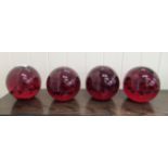 A set of four red coloured glass door stops with interior bubbled ornament  5"h