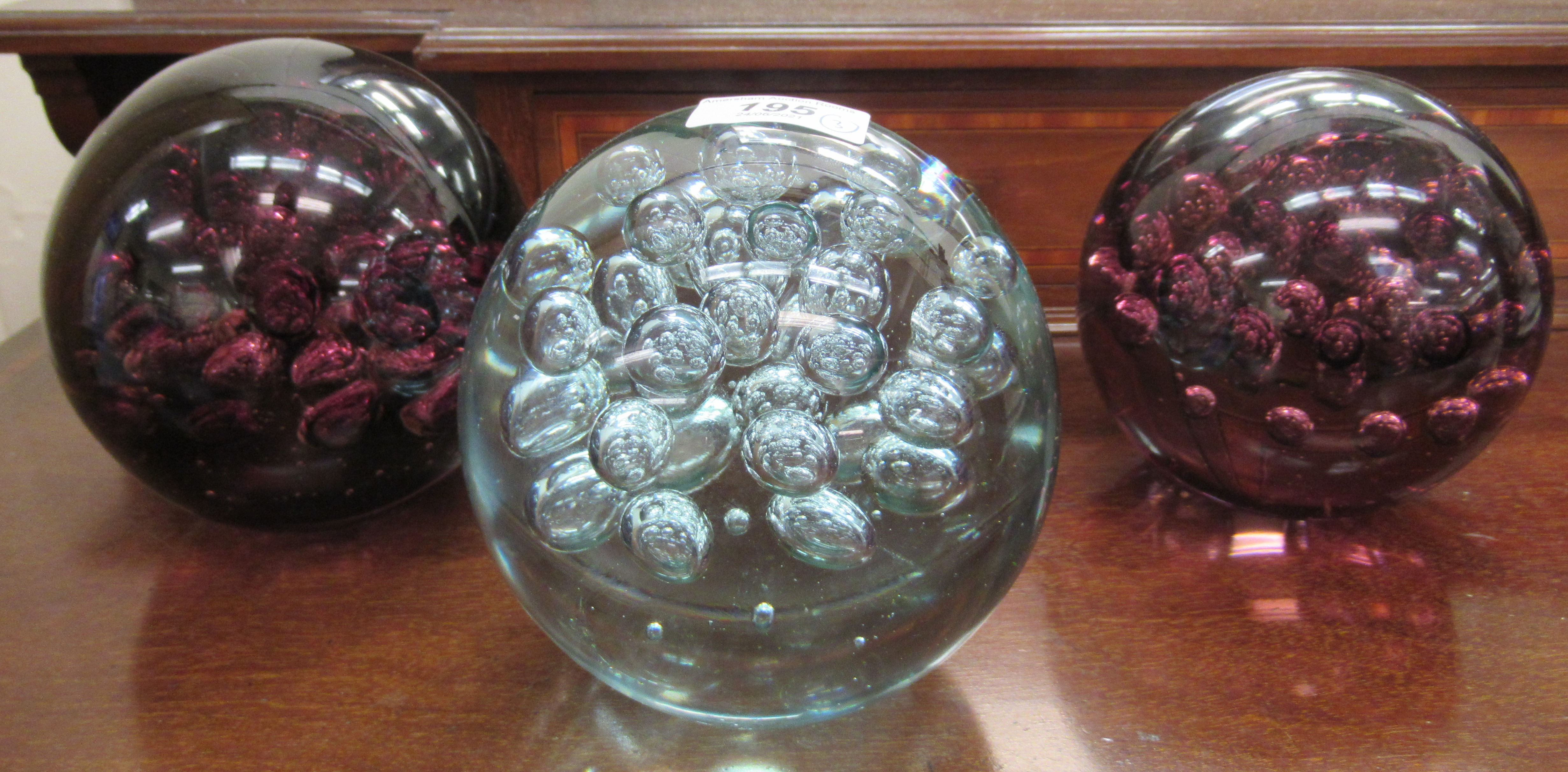 A set of three variously coloured glass doorstops with bubbled decoration  5.5"dia