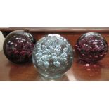 A set of three variously coloured glass doorstops with bubbled decoration  5.5"dia