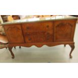 A mid 20thC Waring & Gillows walnut finished sideboard with a carved edge, comprising three drawers,