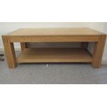 A modern light oak coffee table, raised on square legs, united by an undershelf  18"h  47"w