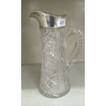 An early 20thC cut crystal cordial jug with a loop handle and applied silver collar with a pouring