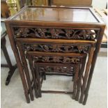 A nesting set of four early 20thC rosewood finished occasional tables, each with a carved frieze,