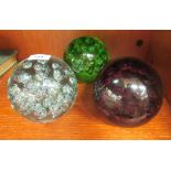 A set of three variously coloured glass doorstops with bubbled decoration  5.5"dia