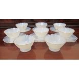 A set of eight milk glass sundae bowls with gilded, wavy rims  6"dia; and six matching plates  6.