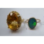 A gold coloured metal dress ring, claw set with a citrine; and a 9ct gold, rubover set with an opal