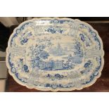 A 19thC earthenware meat plate, having a raised wide, wavy edged border, decorated in blue and white